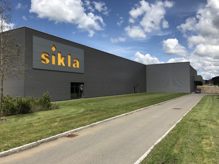 Außenansicht eines modernen Industriegebäudes mit dem gelben Logo der Sikla GmbH in Villingen-Schwenningen auf grauer Fassade.