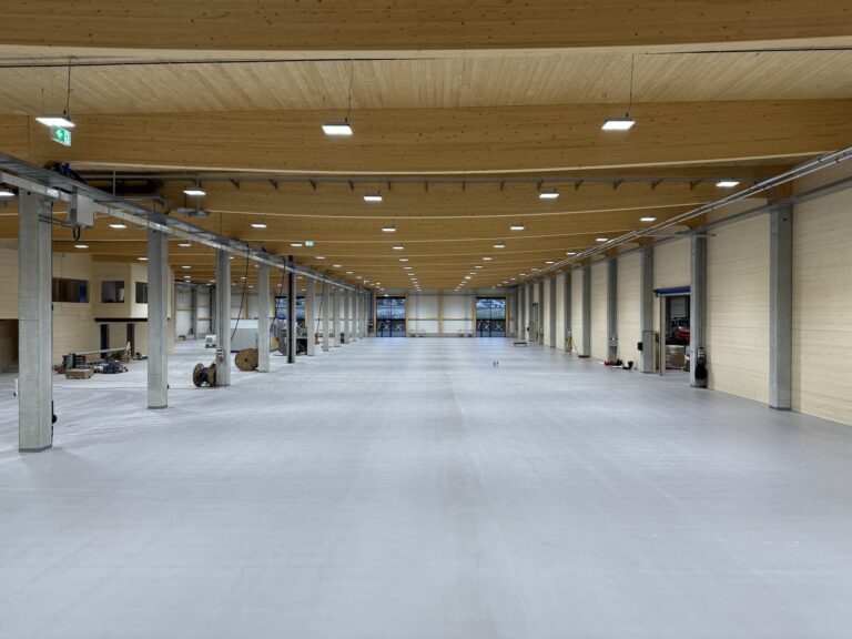 Weitläufige Produktionshalle Kauth Neubau Denkingen mit modernen Holzdecken und Betonstützen.