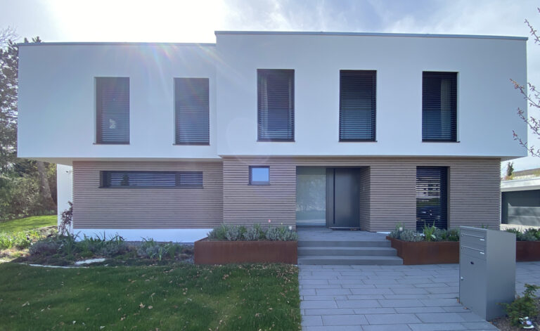 Modernes zweistöckiges Wohnhaus mit weißer Fassade, Holzpaneelen, vertikalen Fenstern und gepflegtem Garten in Villingen-Schwenningen. Architekten haben das Haus modernisiert.
