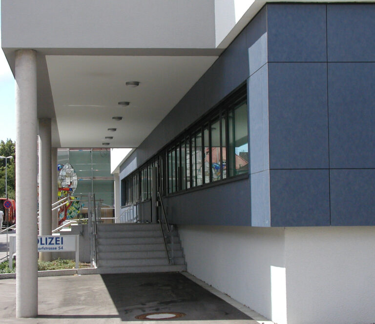Der Neubau des Polizeigebäudes in Schwenningen mit einer überdachten Eingangsrampe und blauen Wandpaneelen.